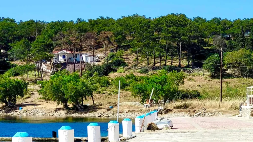 Waterfront promenade and natural landscape with trees and hillside on Telendos Island Greece