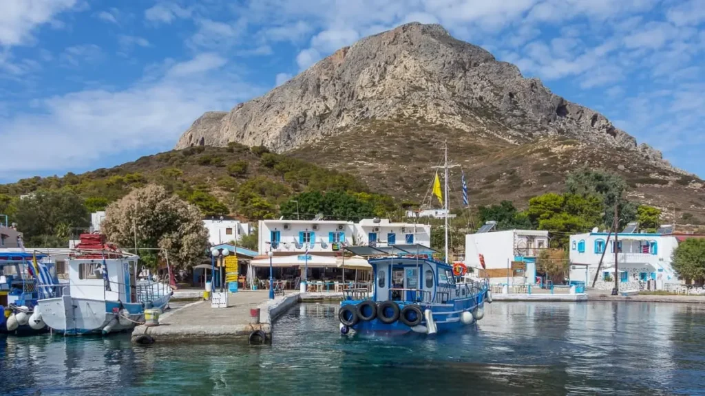 Traditional fishing boats at Telendos harbor with mountain backdrop near Sylvia House accommodation